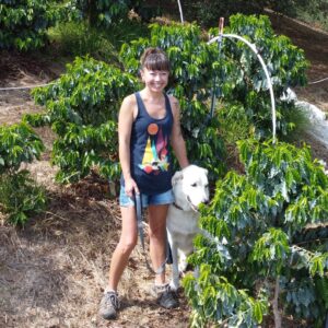 One of Foggy Oaks' owners with her dog in a field of coffee trees.